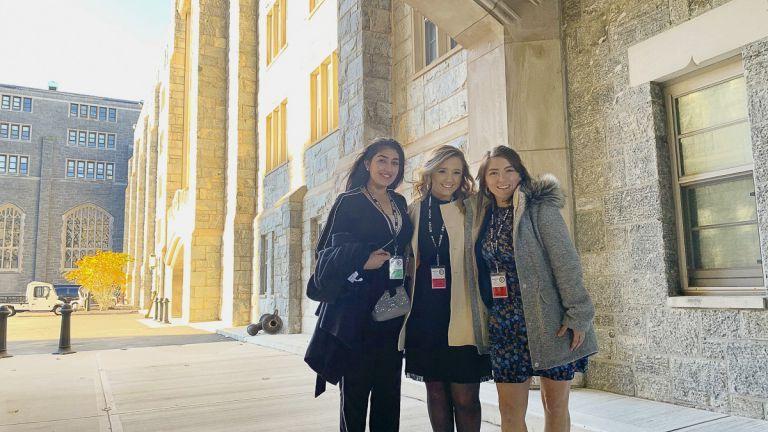 smiling students standing in front of West Point building